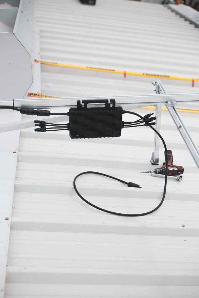 Close-up of solar charge controller installation with cables on a metal roof.