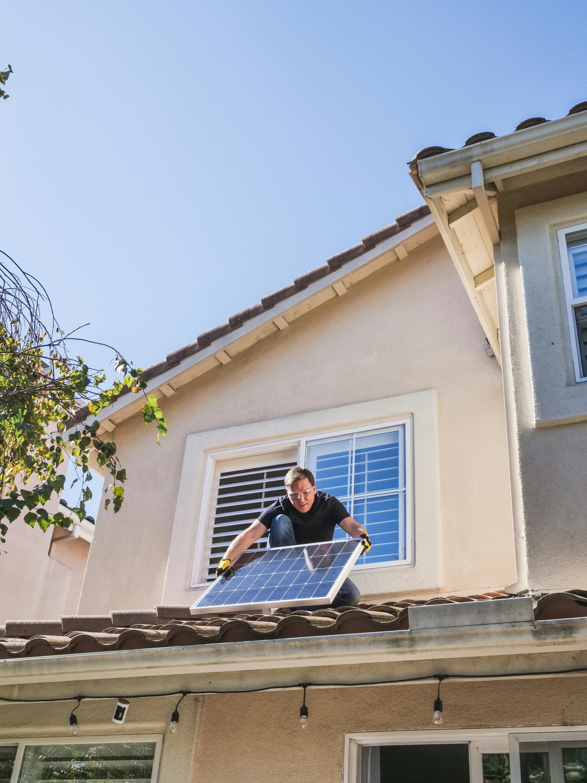 A worker installs a solar panel on a residential rooftop, showcasing renewable energy technology.